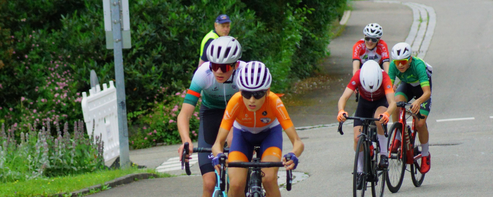 Jugendliche Radfahrer mit orangefarbigem Trikot vorn beim U15-Rennen