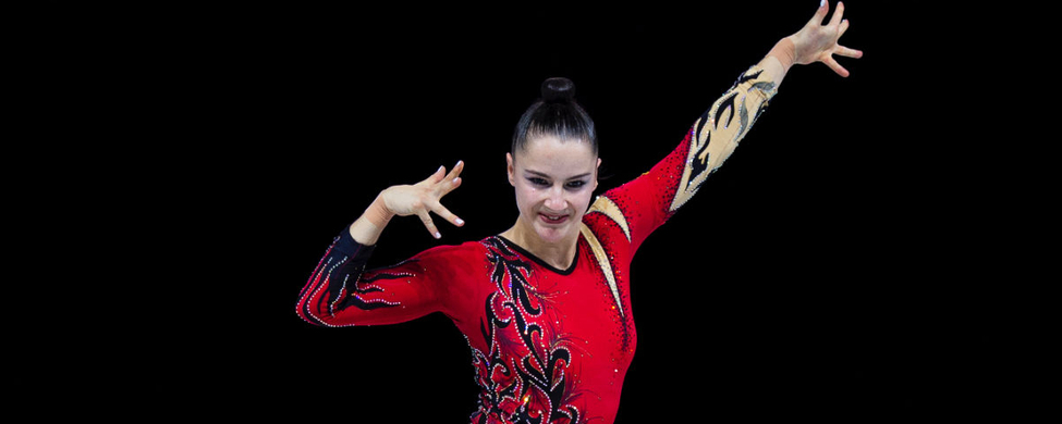 Aerobic-Athletin in rotem Wettkampfanzug kniend in dynamischer Pose