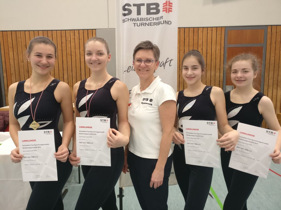 Vier Gymnastinnen mit Urkunden und Trainerin vor STB-Banner