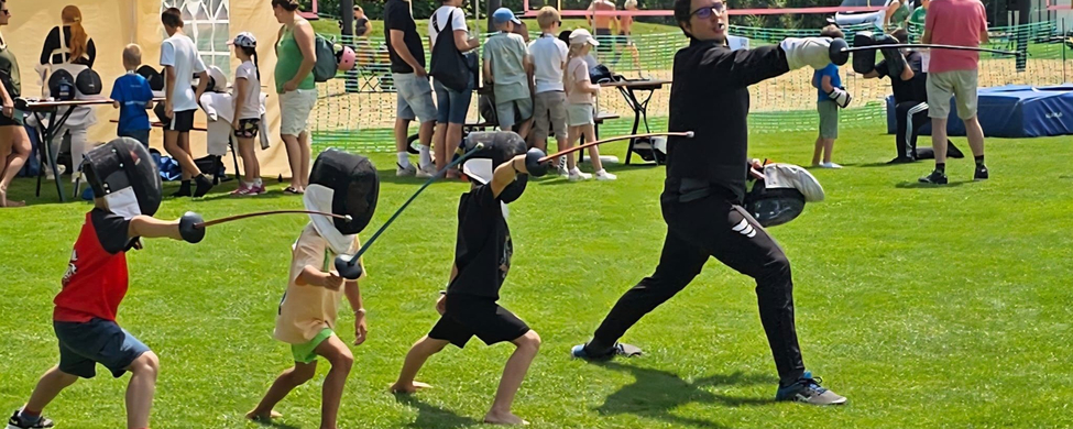 Trainer zeigt Kindern Fechtübung bei Mitmach-Sportfest
