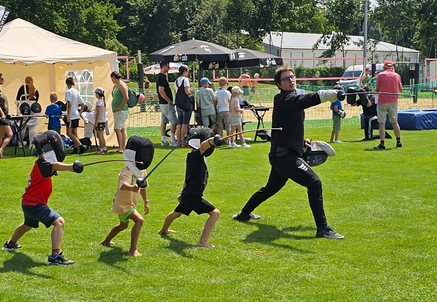 Trainer zeigt Kindern Fechtübung bei Mitmach-Sportfest