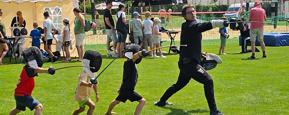 Trainer zeigt Kindern Fechtübung bei Mitmach-Sportfest