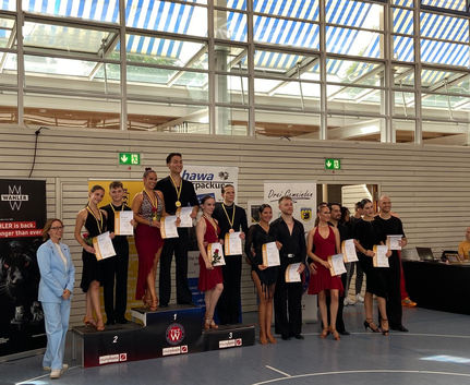 Tanzpaare mit Medaillen und Urkunden auf Siegerpodest in Sporthalle