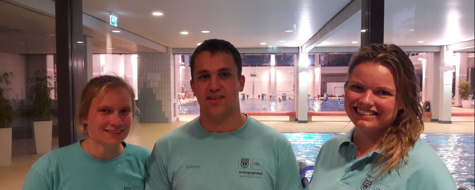Drei SwimStars-Instruktoren in türkis T-Shirts vor Schwimmbecken