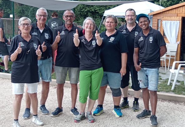Eight team members in black shirts giving thumbs up outdoors