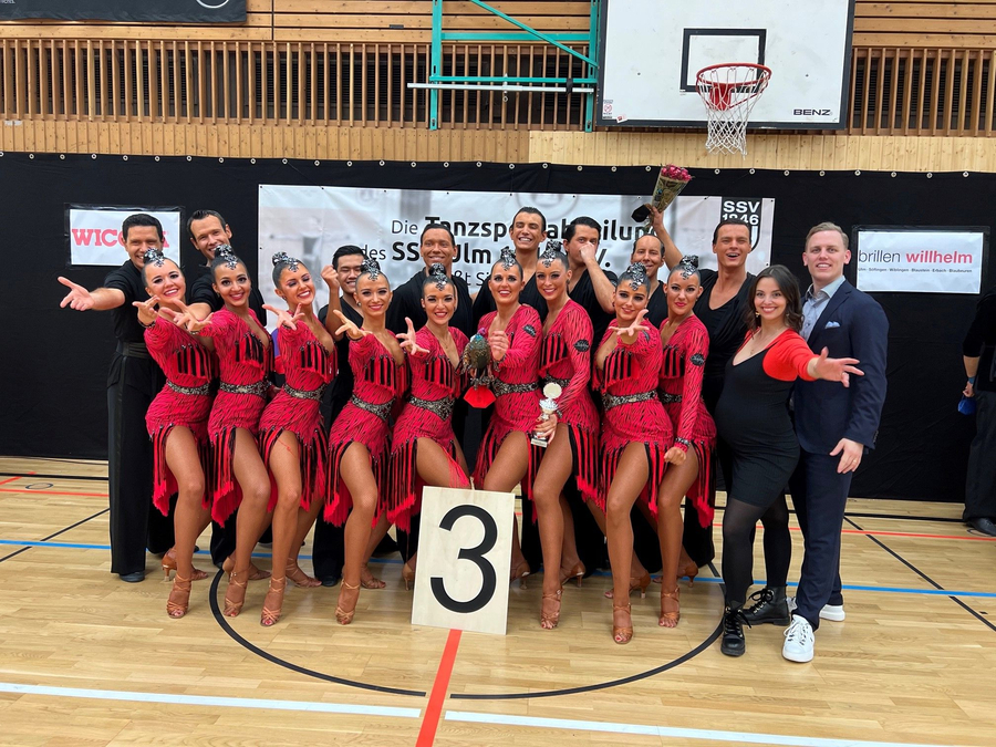 Formations-Team in roten Kostümen posiert mit Schild 3