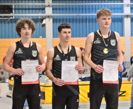 Drei jugendliche Leichtathleten in Teamtrikots mit Urkunden und Medaillen