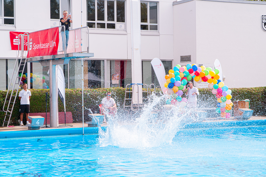 Ein Teilnehmer beim 1. Ulmer Arschbomben-Contest powered by Sparkasse Ulm springt vom 3-m-Turm und man sieht auf dem Bild den Moment, wo er ins Wasser eintaucht und seine Arschbombe eine ordentliche Wasserfontäne erzeugt.