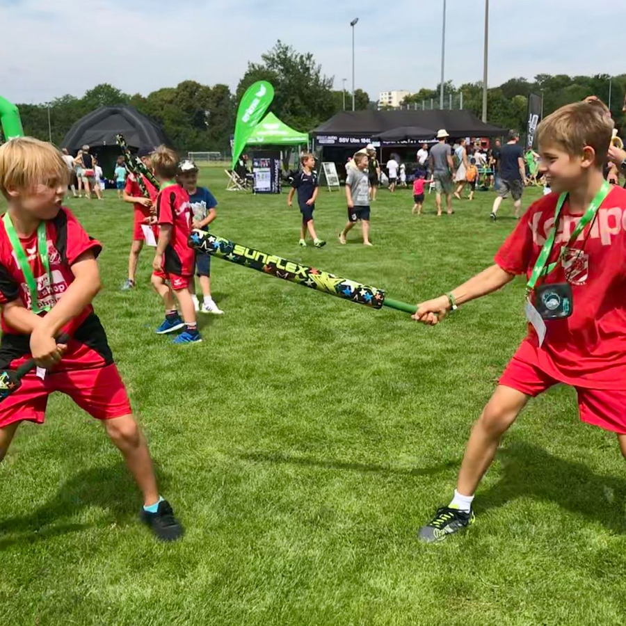 Zwei Kinder in roten Trikots duellieren mit Schaumstoffschwertern SUNFLEX