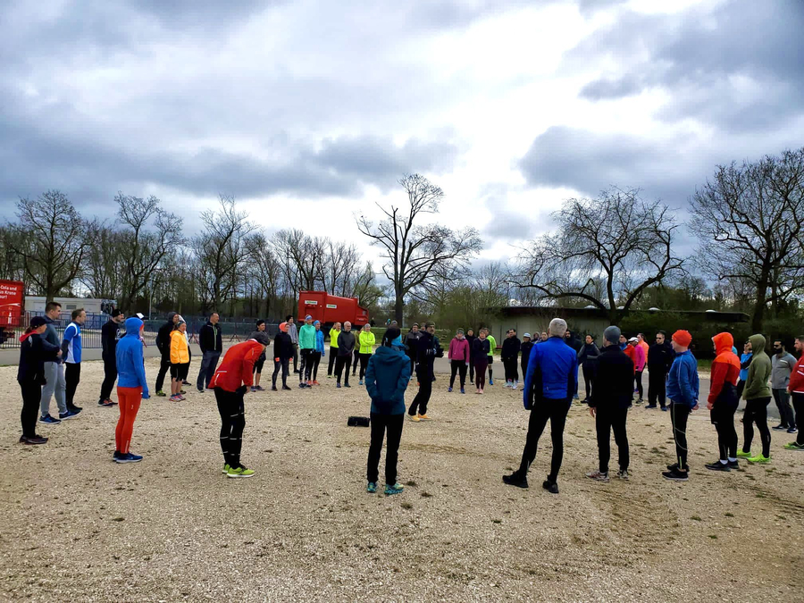 Große Gruppe Läufer in Sportkleidung steht im Kreis bei Outdoor-Workshop