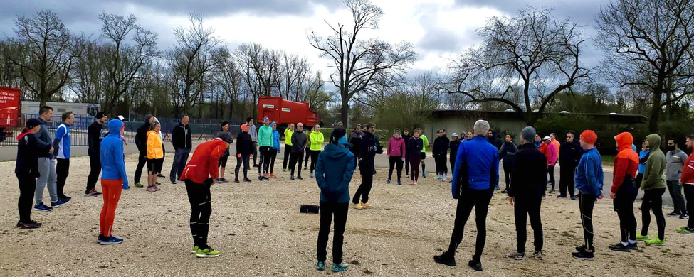 Große Gruppe Läufer in Sportkleidung steht im Kreis bei Outdoor-Workshop