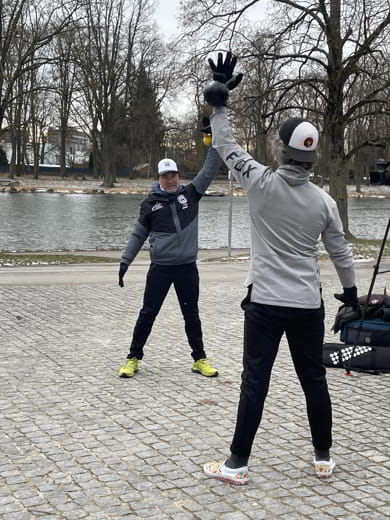 Zwei Männer beim Outdoortraining mit Kettlebell am Flussufer bei winterlichem Wetter