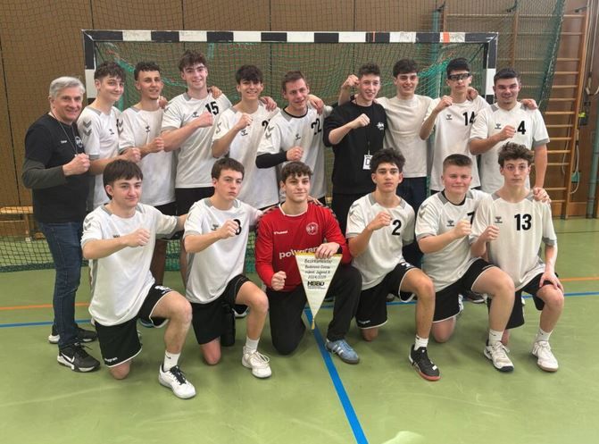 Jugendhandballmannschaft posiert vor Tor mit Wimpel und Fäusten