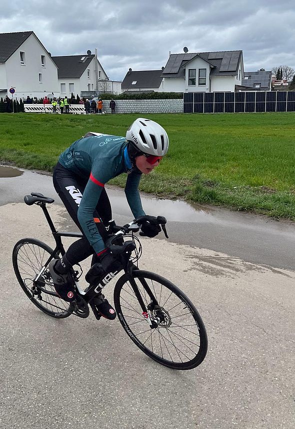 Radsportler in Teamtrikot auf nasser Straße beim Rennen