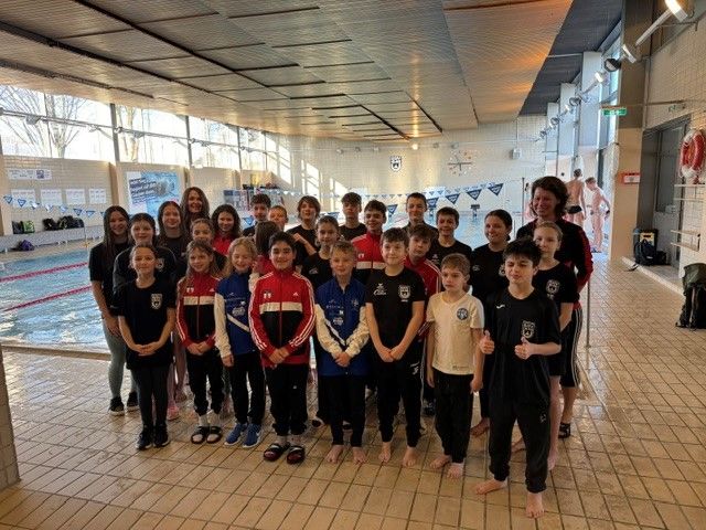 Gruppe jugendlicher Schwimmerinnen und Schwimmer am Hallenbadrand