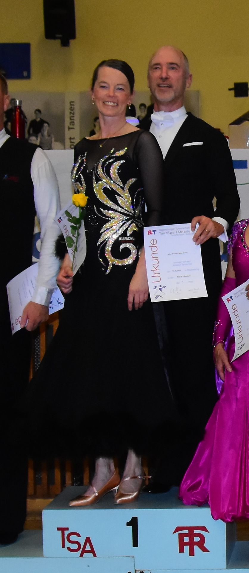 Tanzpaar Bernhard und Martina Müller auf Siegerpodest mit Urkunde und Rose